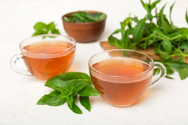 Cup of mint tea on table background. Green tea with fresh mint top view with copy space.