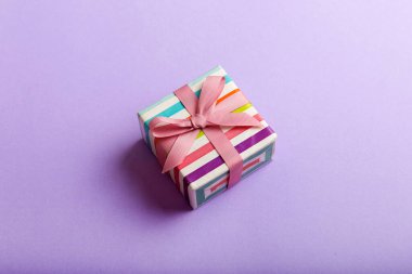 Noel 'i ya da diğer tatil hediyelerini renkli arka planda kurdeleyle renkli kağıda sardım. Şimdiki kutu, renkli tabloda hediye süslemesi, kopya alanı ile üst görünüm.