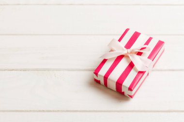 Noel 'i ya da diğer tatil hediyelerini renkli arka planda kurdeleyle renkli kağıda sardım. Şimdiki kutu, renkli tabloda hediye süslemesi, kopya alanı ile üst görünüm.