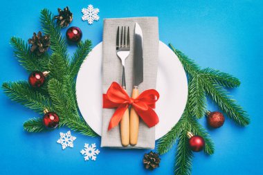 Noel süsleri, tabaklar, inekler, çatallar ve kaşıklarla Noel sofrası. Noel tatili geçmişi. Üst görünüm.