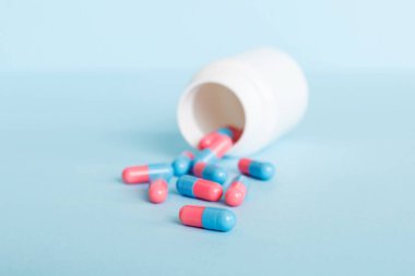 Renkli arka planda haplarla dolu plastik ilaç şişesi. İnternetteki eczane. Ağrı kesici ilaç ve antibiyotik ilaç direnci konsepti. İlaç endüstrisi..