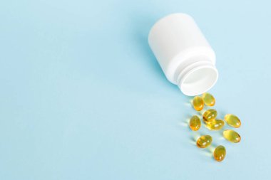 Yumuşak jel hapları ve Omega-3 yağı hap şişesinden sızıyor. Jel kapsülleri beyaz yüzey şişesi. Omega 3, multivitamin, kalsiyum, antibiyotik. Sağlığa. Dokunulmazlık.