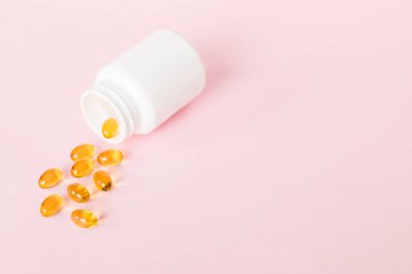 Yumuşak jel hapları ve Omega-3 yağı hap şişesinden sızıyor. Jel kapsülleri beyaz yüzey şişesi. Omega 3, multivitamin, kalsiyum, antibiyotik. Sağlığa. Dokunulmazlık.