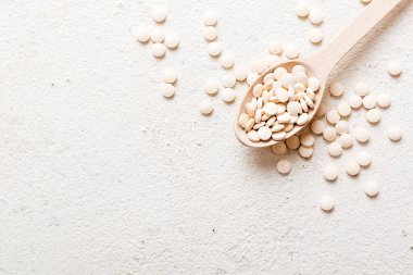 Renkli arka planda bir yığın beyaz hap. Tabletler masaya saçılmış. Kırmızı yumuşak jelatin kapsül yığını. Vitaminler ve beslenme takviyeleri konsepti.