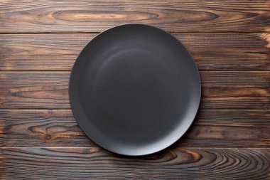Ahşap arka plandaki siyah plakanın üst görüntüsü. Tasarımın için boş boşluk.