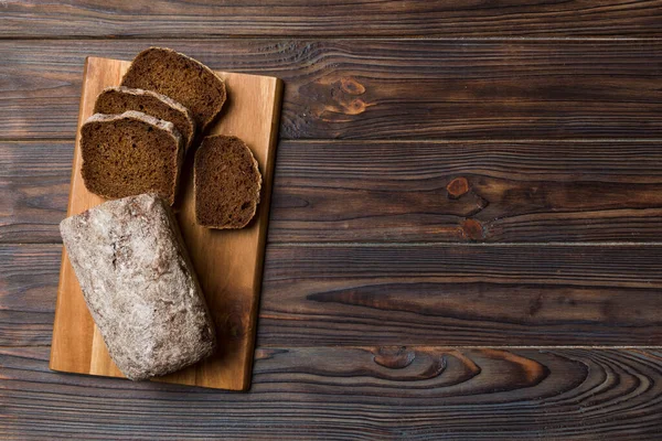 Freshly baked bread slices on cutting board against white wooden background. top view Sliced bread.