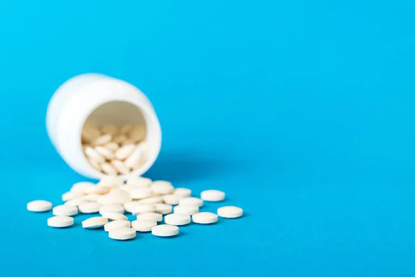 Medicine bottle and white pills spilled on a light background. Medicines and prescription pills flat lay background. White medical pills and tablets spilling out of a drug bottle.