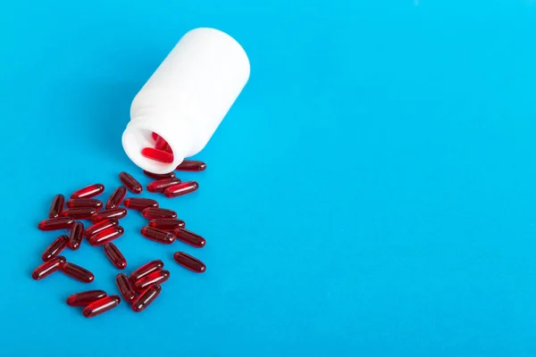 Red pills spilled around a pill bottle. Medicines and prescription pills flat lay background. Red medical capsules.