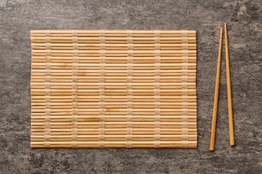 Çimento arka planında iki çubuk ve bambu paspas. Üst görünüm, alanı kopyala.