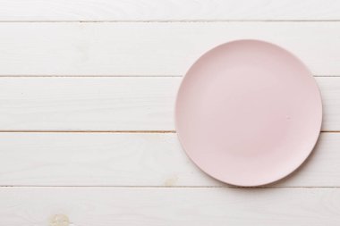 Ahşap arka planda boş pembe tabağın üst görüntüsü. Tasarımın için boş boşluk.