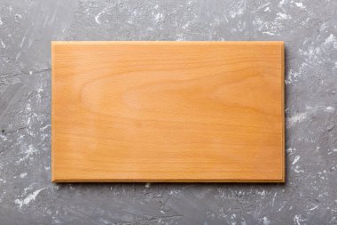 Çimento arka planında ahşap kesim tahtasının üst görüntüsü. Tasarımın için boş boşluk.