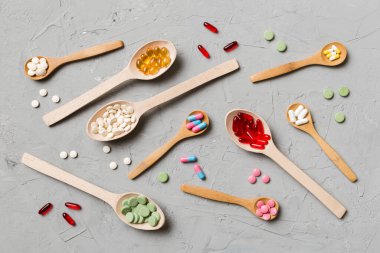 Renkli arka planda tahta kaşıkta vitamin ve mineral haplarının üst görünümü. Muhtelif ilaç haplarının en üst görüntüsü. Beslenme takviyesi sağlık ürünleri.