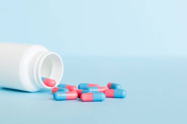 Renkli arka planda haplarla dolu plastik ilaç şişesi. İnternetteki eczane. Ağrı kesici ilaç ve antibiyotik ilaç direnci konsepti. İlaç endüstrisi..