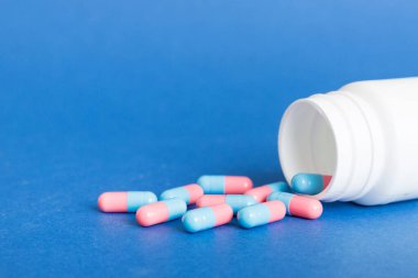 Renkli arka planda haplarla dolu plastik ilaç şişesi. İnternetteki eczane. Ağrı kesici ilaç ve antibiyotik ilaç direnci konsepti. İlaç endüstrisi..
