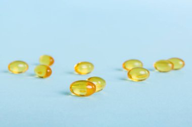 Heap of yellov pills on colored background. Tablets scattered on a table. Pile of red soft gelatin capsule. Vitamins and dietary supplements concept.