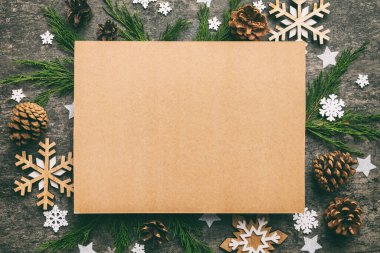 Noel kompozisyonu düzdü. Kare kağıt boş, çam ağacı dalları, renkli arka planda noel süslemeleri. Üst görünüm, metin için boşluk kopyala.