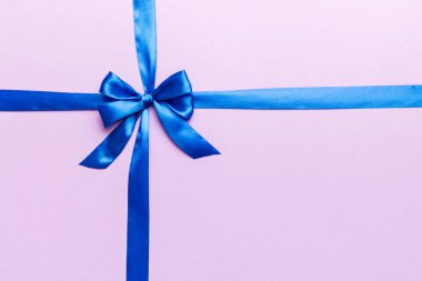 Mor kurdelenin üst görüntüsü yuvarlandı ve pembe fiyonk renkli arka planda izole edildi. Kopyalama alanı olan düz.