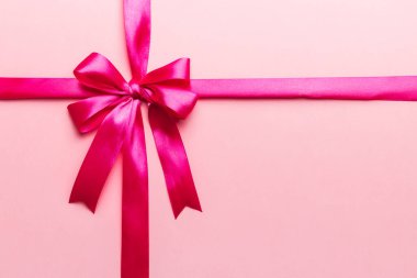 Mor kurdelenin üst görüntüsü yuvarlandı ve pembe fiyonk renkli arka planda izole edildi. Kopyalama alanı olan düz.