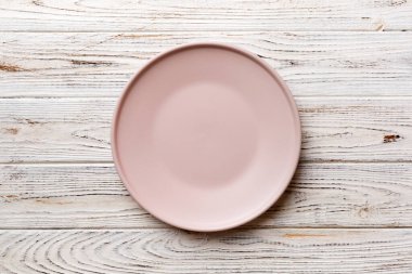 Ahşap arka planda boş pembe tabağın üst görüntüsü. Tasarımın için boş boşluk.