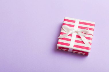 Noel 'i ya da diğer tatil hediyelerini renkli arka planda kurdeleyle renkli kağıda sardım. Şimdiki kutu, renkli tabloda hediye süslemesi, kopya alanı ile üst görünüm.