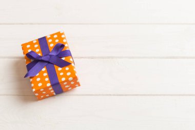 Renkli arka planda mor kurdeleli Noel ya da diğer tatil hediyelerini kağıda sardım. Şimdiki kutu, renkli tabloda hediye süslemesi, kopya alanı ile üst görünüm.