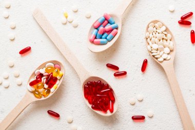 Renkli bir arka planda kaşıkta vitamin kapsülleri. Haplar sağlıklı bir yemek olarak sunuldu. Kırmızı yumuşak jel vitamin takviye kapsülleri kaşık üzerinde.
