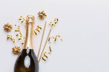 Gözlüklü bir şişe şampanya ve renkli arka planda renkli konfeti. Üst görünüm yatıyordu.