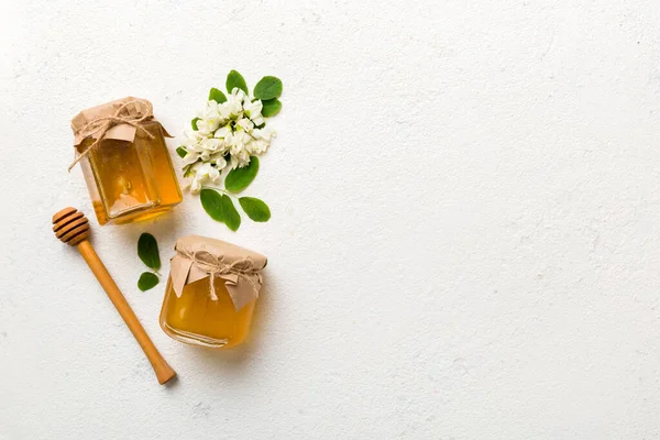 Akasya çiçekli ve yapraklı bal kavanozu. Taze bal üst görünüm düz yatıyordu.