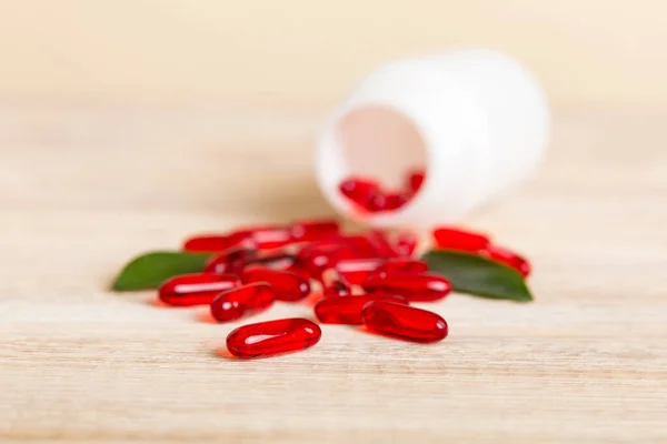 Red pills spilled around a pill bottle. Medicines and prescription pills flat lay background. Red medical capsules.