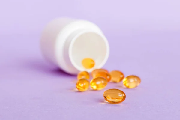 Soft gels pills with Omega-3 oil spilling out of pill bottle close-up. Gel capsules bottle white surface. Omega 3, multivitamins, Calcium, antibiotics. Health. Immunity.