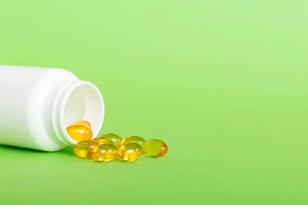 Soft gels pills with Omega-3 oil spilling out of pill bottle close-up. Gel capsules bottle white surface. Omega 3, multivitamins, Calcium, antibiotics. Health. Immunity.