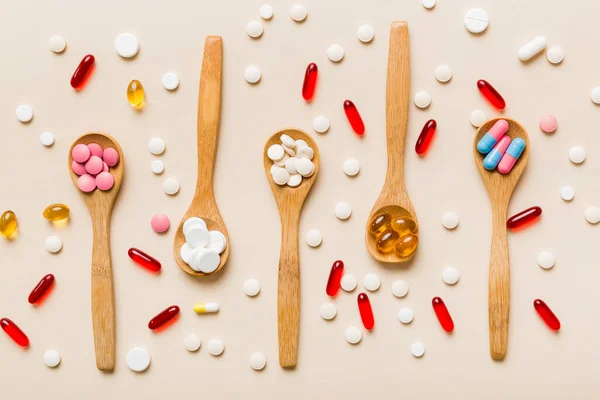 Vitamin capsules in a spoon on a colored background. Pills served as a healthy meal. Red soft gel vitamin supplement capsules on spoon.