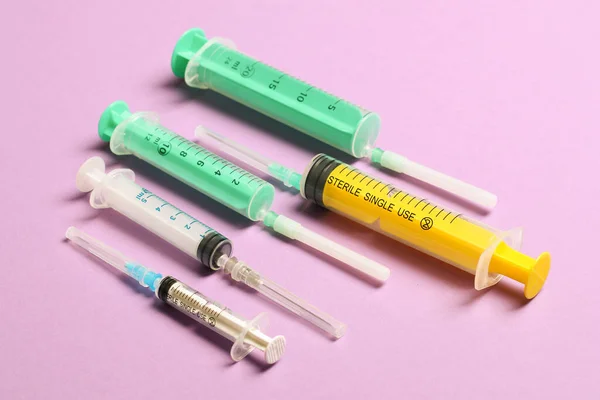Top view of medical syringes with needles at purple background with copy space. Injection treatment concept.