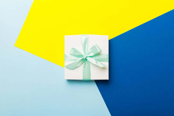 holiday handmade white present tied green ribbon bow top view with copy space. Flat lay holiday background. Birthday or christmas present. Christmas gift box concept with copy space.