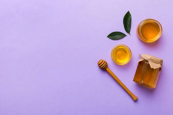 Honey jar with wooden honey dipper on white background top view with copy space. Delicious honey bottle.