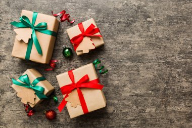 wrapped christmas or other holiday handmade present in paper with colored ribbon. Present box, decoration of gift on colourfull table, top view with copy space.