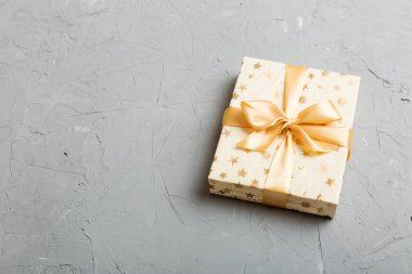 Noel 'i ya da diğer tatil hediyelerini renkli arka planda altın kurdeleli beyaz kağıda sardım. Şimdiki kutu, renkli tabloda hediye süslemesi, kopya alanı ile üst görünüm.