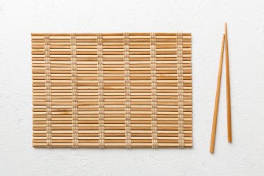 Çimento arka planında iki çubuk ve bambu paspas. Üst görünüm, alanı kopyala.