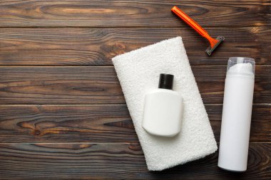 Tıraş Adam seti. Traş makinesi, havlu, losyon ve renkli arka planda tıraş köpüğü. Erkekler banyo aksesuarları üst görünüm.