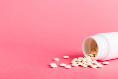 Medicine bottle and white pills spilled on a light background. Medicines and prescription pills flat lay background. White medical pills and tablets spilling out of a drug bottle.
