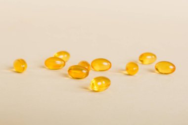 Heap of yellov pills on colored background. Tablets scattered on a table. Pile of red soft gelatin capsule. Vitamins and dietary supplements concept.