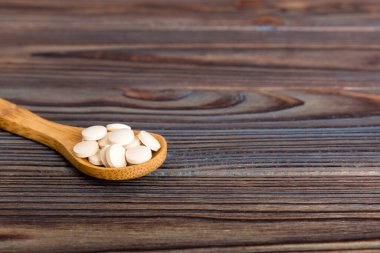 Renkli arka planda bir yığın beyaz hap. Tabletler masaya saçılmış. Kırmızı yumuşak jelatin kapsül yığını. Vitaminler ve beslenme takviyeleri konsepti.