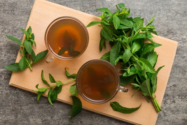 Cup of mint tea on table background. Green tea with fresh mint top view with copy space.