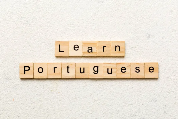 learn portuguese word written on wood block. learn portuguese text on table, concept.