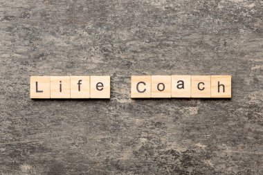 Tahta blokta yaşam koçu kelimesi yazıyor. Yaşam koçu desing, konsept için çimento masa üzerinde metin.