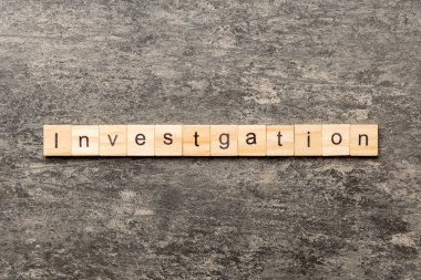 Tahta blokta yazılı soruşturma kelimesi. soruşturma metni masa üzerinde, konsept.