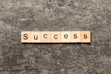 Tahta blokta yazan başarı kelimesi. Masada başarı metni, konsept.