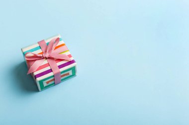 Noel 'i ya da diğer tatil hediyelerini renkli arka planda kurdeleyle renkli kağıda sardım. Şimdiki kutu, renkli tabloda hediye süslemesi, kopya alanı ile üst görünüm.