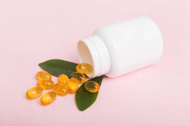 Omega-3 kapsülleri masa arkasında beyaz bir şişede yatıyor. Balık yağı tabletlerinin üst görüntüsü. Biyolojik olarak aktif katkı maddeleri. omega 6, omega 9, A vitamini, D vitamini, D3 vitamini, akşam çuha çiçeği yağı.