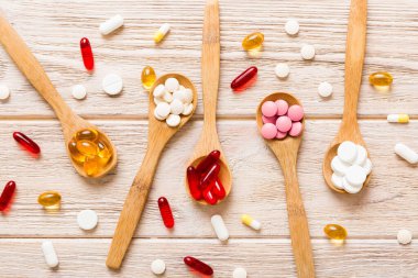 Renkli bir arka planda kaşıkta vitamin kapsülleri. Haplar sağlıklı bir yemek olarak sunuldu. Kırmızı yumuşak jel vitamin takviye kapsülleri kaşık üzerinde.
